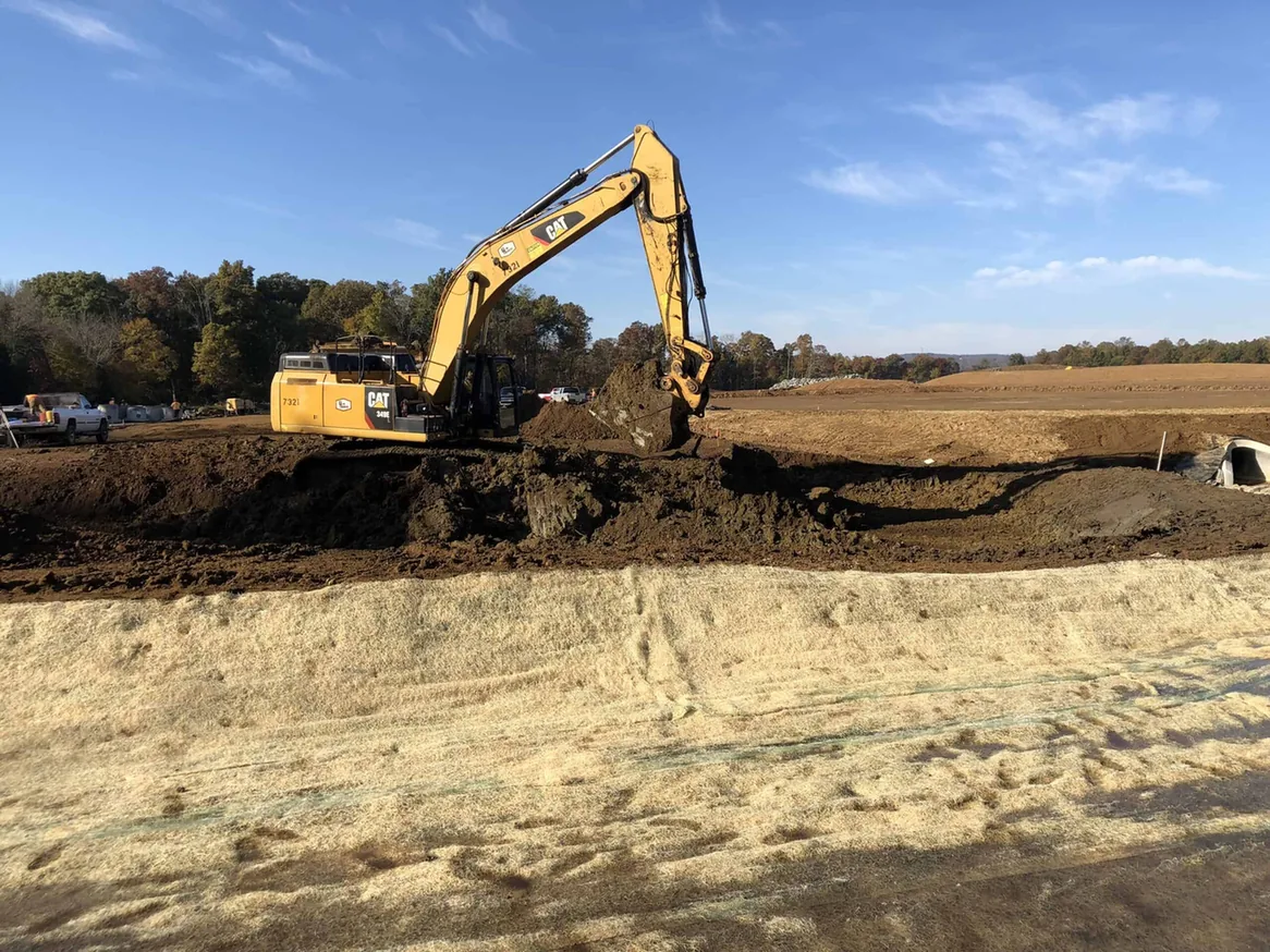 Large excavator mass excavating a graded development site, commercial site work