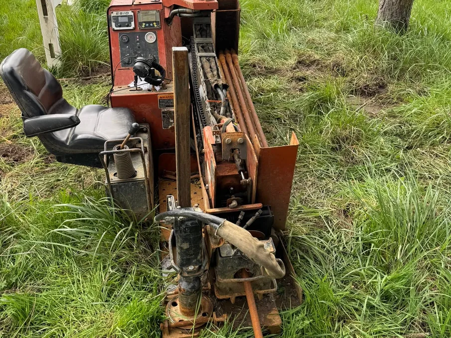 Directional drill rig with its drill rods racked, set up on grass, directional drilling