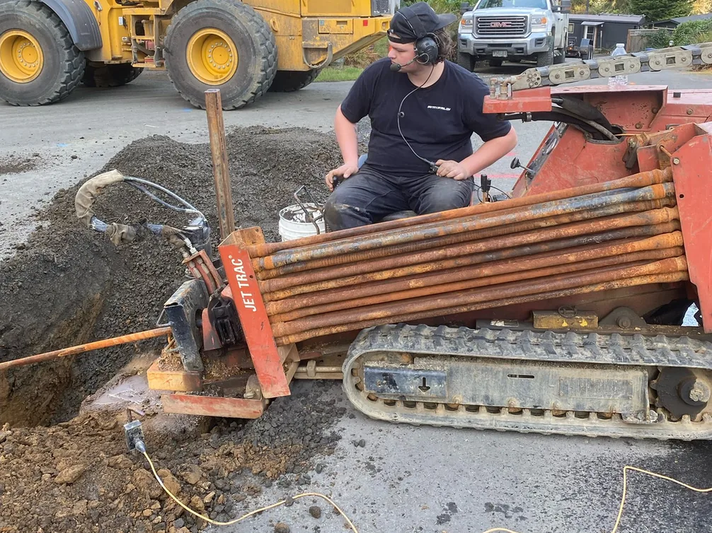 Crew member running a directional drill rig beside a bore pit, directional drilling