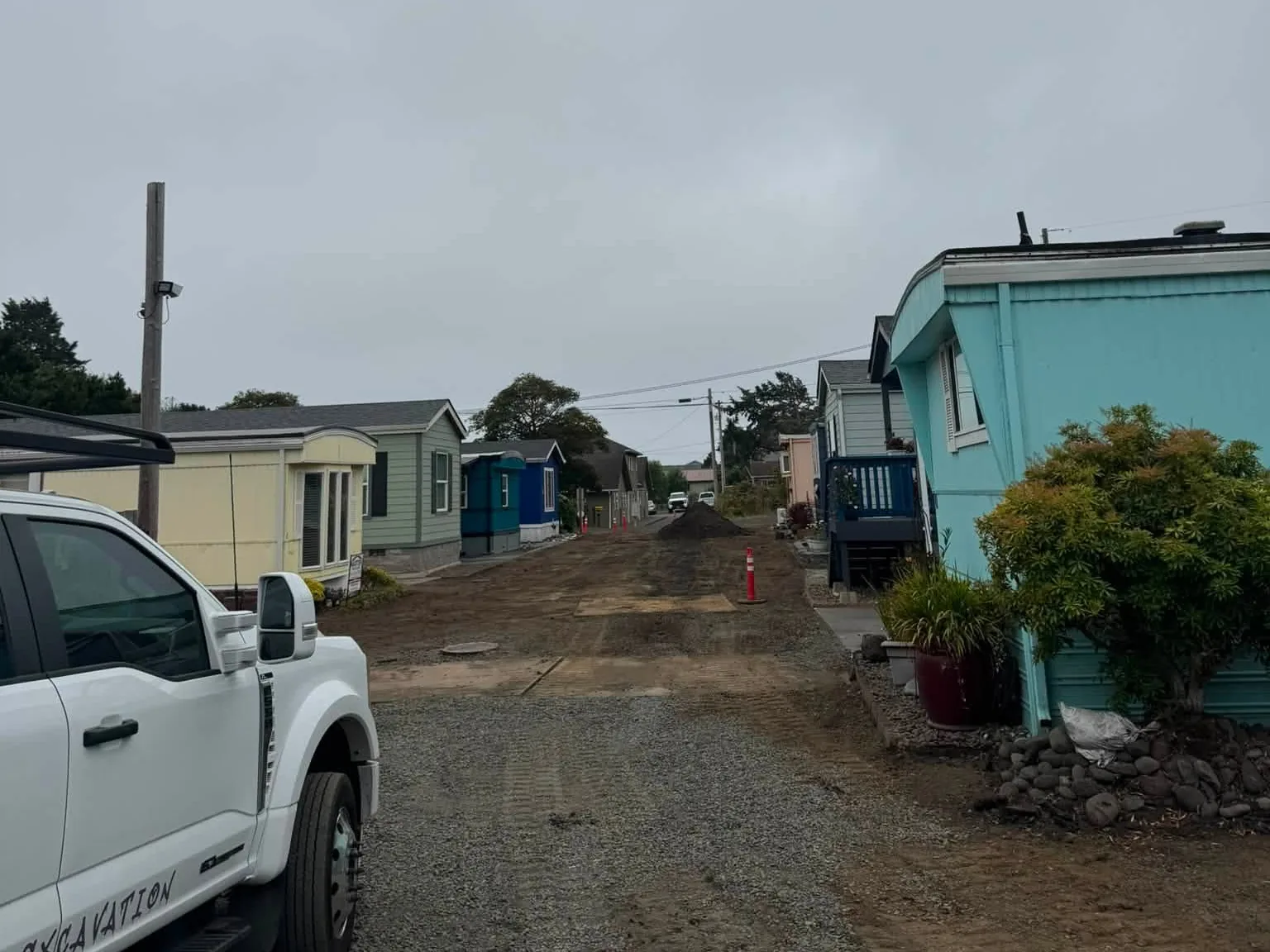 Gravel lane between homes with a work pickup beside it, driveways access roads