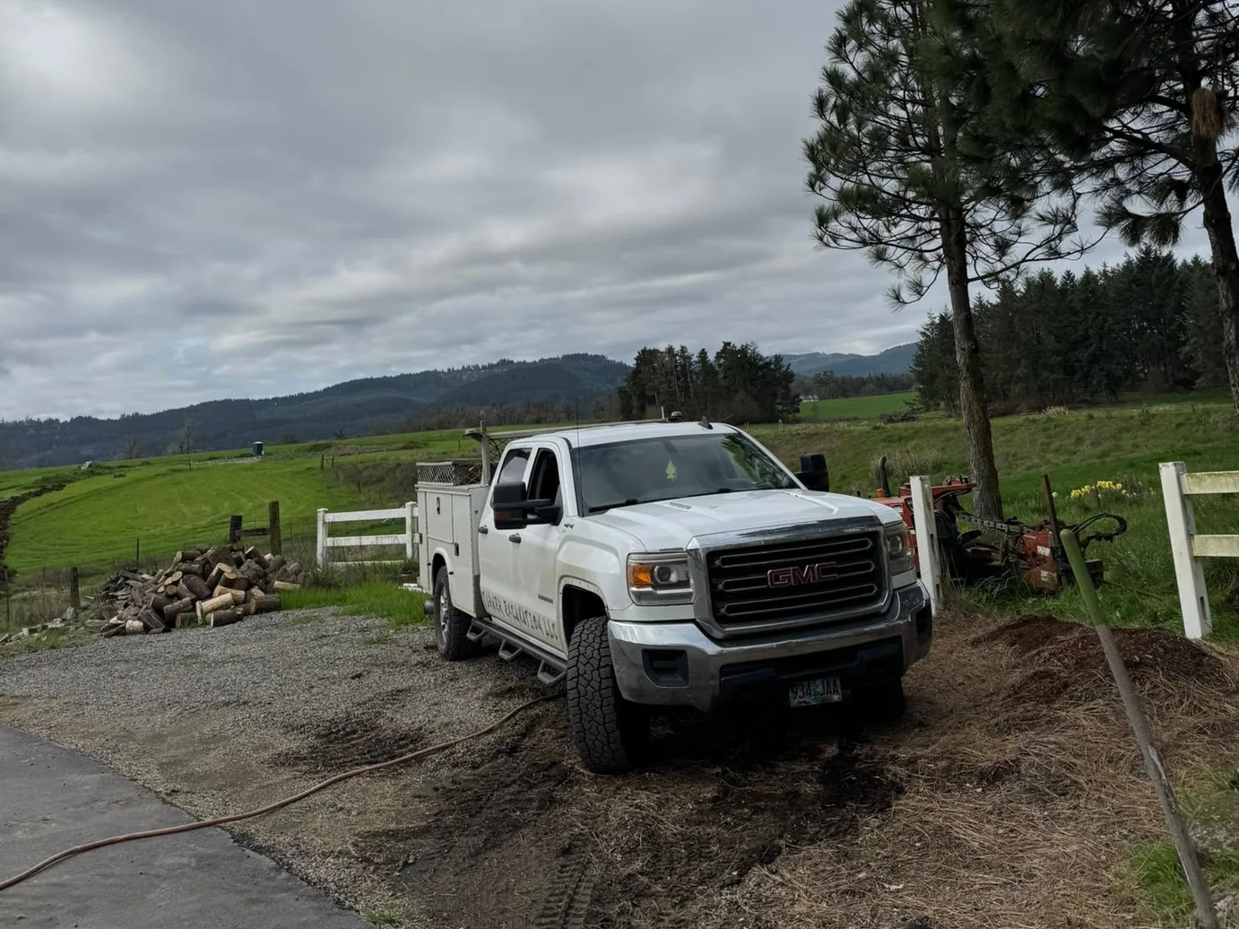 Work pickup on a gravel rural drive beside a field, driveways access roads
