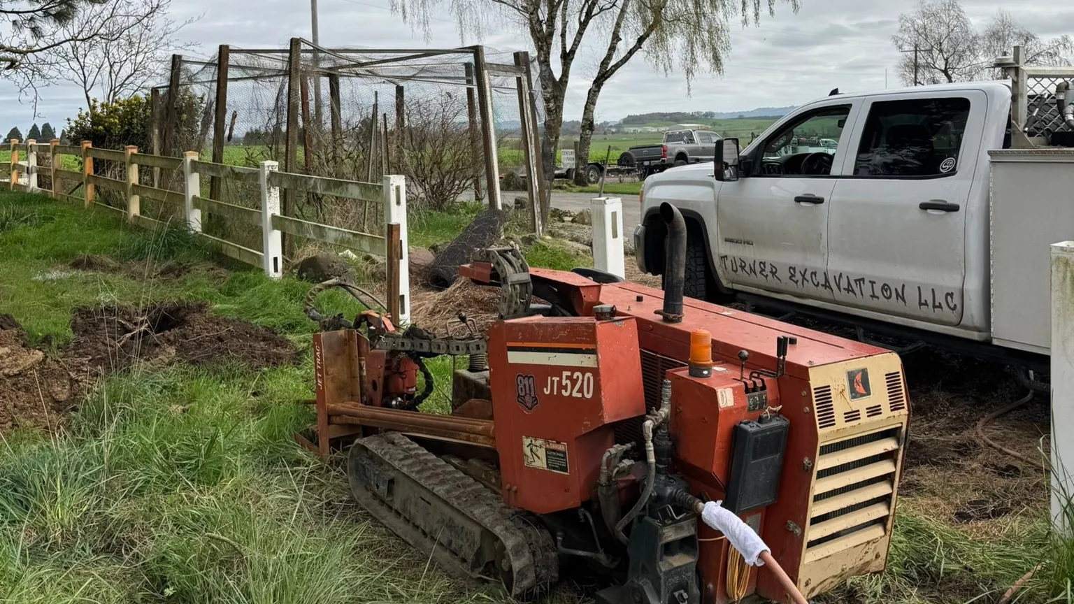 Directional drill rig on grass beside a work pickup, excavation contractor