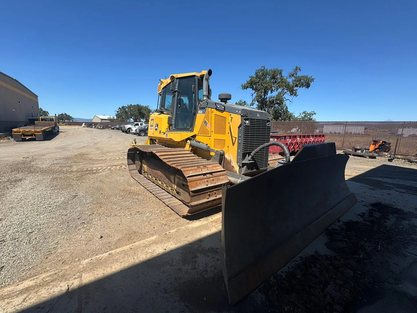 Dozer with its blade down on a gravel yard, grading earthwork
