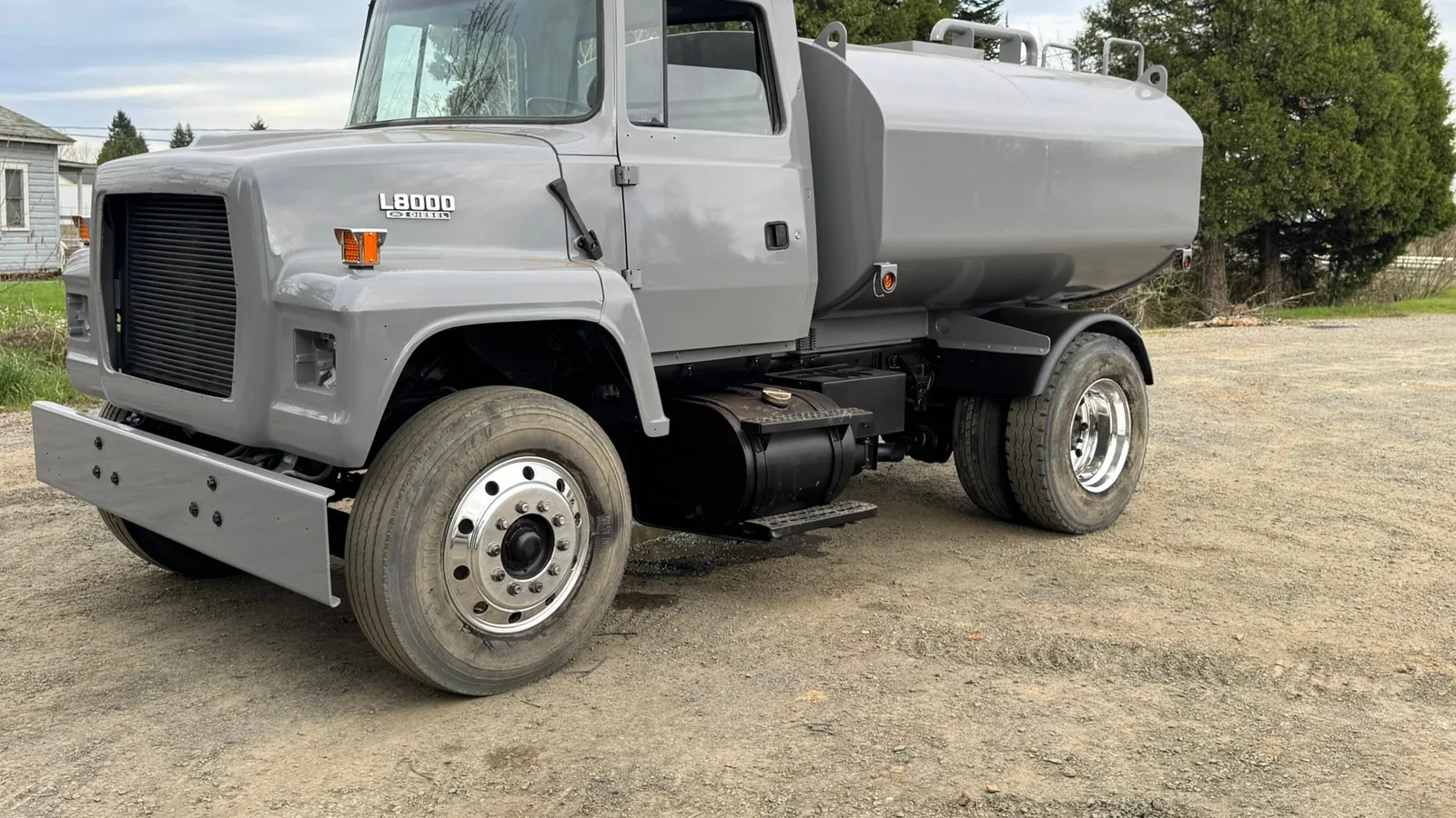 Gray water truck parked on a gravel yard, excavation contractor service areas
